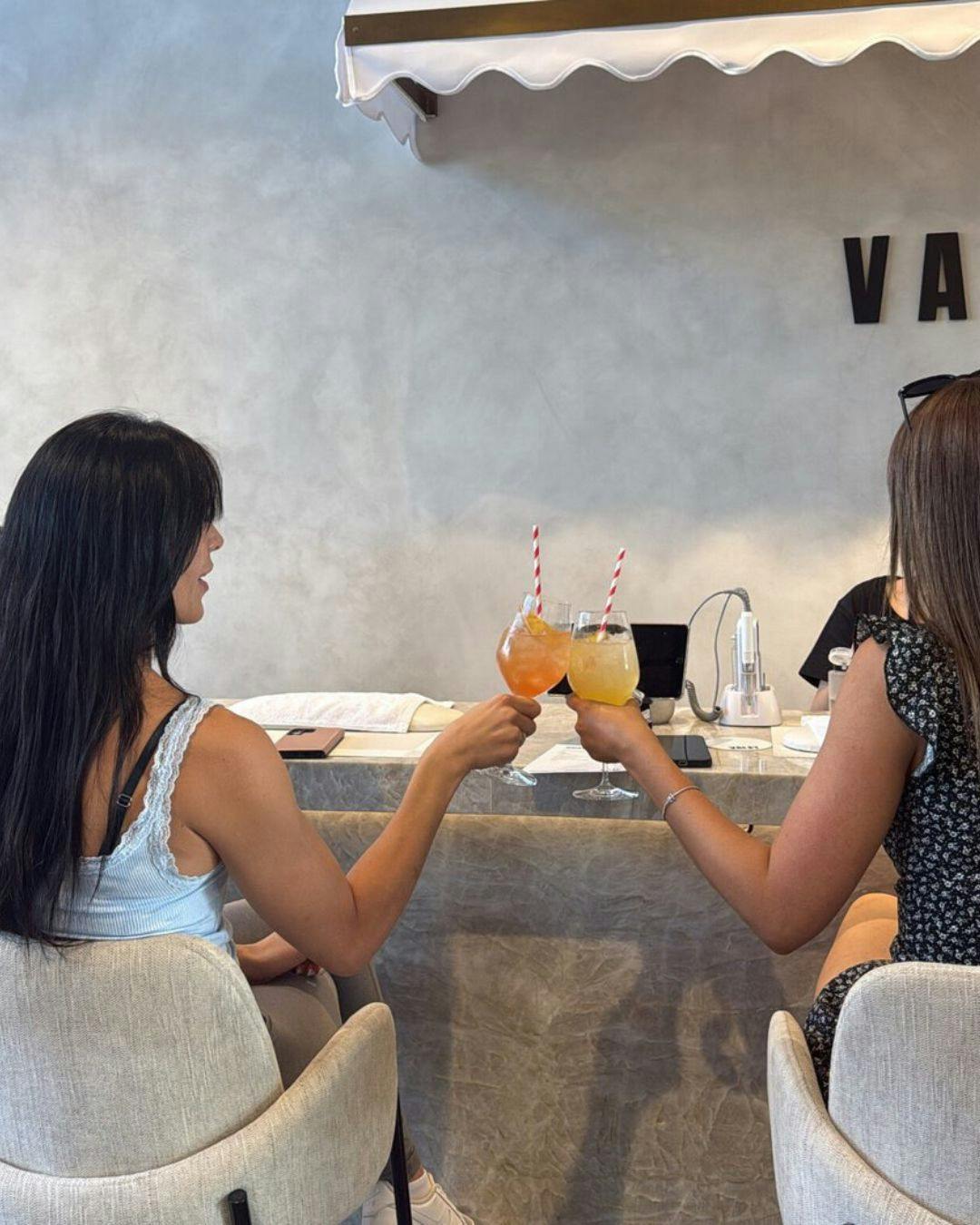 Two friends enjoying a cheeky cocktail while getting their nails done at Valet.